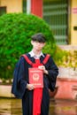 Man in Black Academic Dress Holding Red Paper