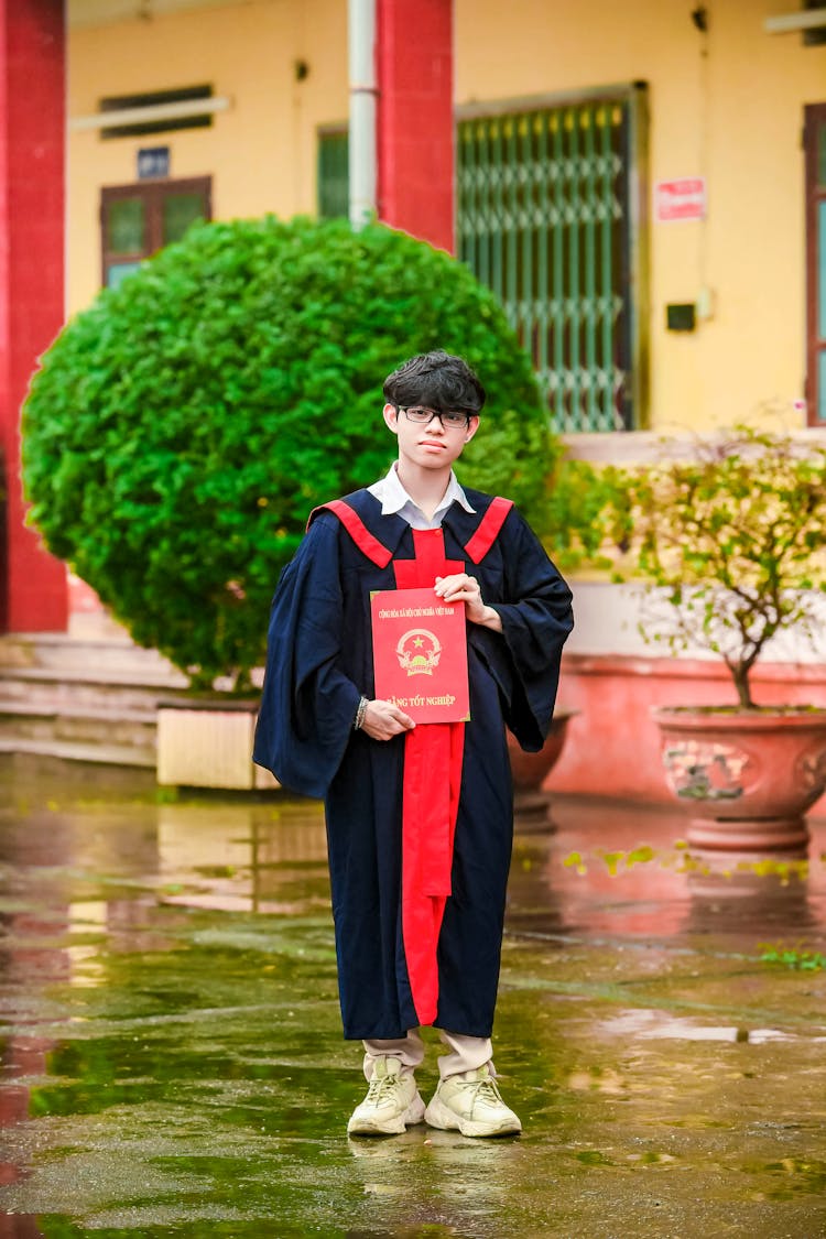 A Teenage Boy Wearing A Graduation Toga