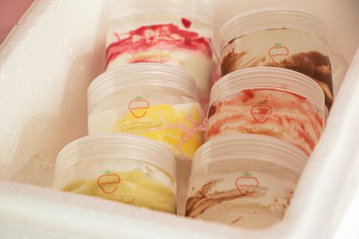 Colorful assortment of creamy ice cream in plastic tubs, perfect for a sweet chilled treat.