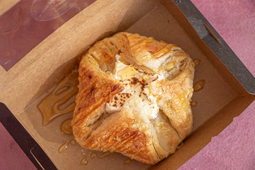 A freshly baked puff pastry box drizzled with honey over cream cheese, perfect for a sweet treat.