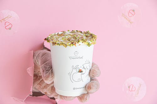 Hand with Takeaway Cup with Coffee on Pink Background