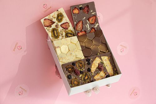 Free Artisan chocolate bars with fruit and nut toppings in a stylish box on a pink background. Stock Photo