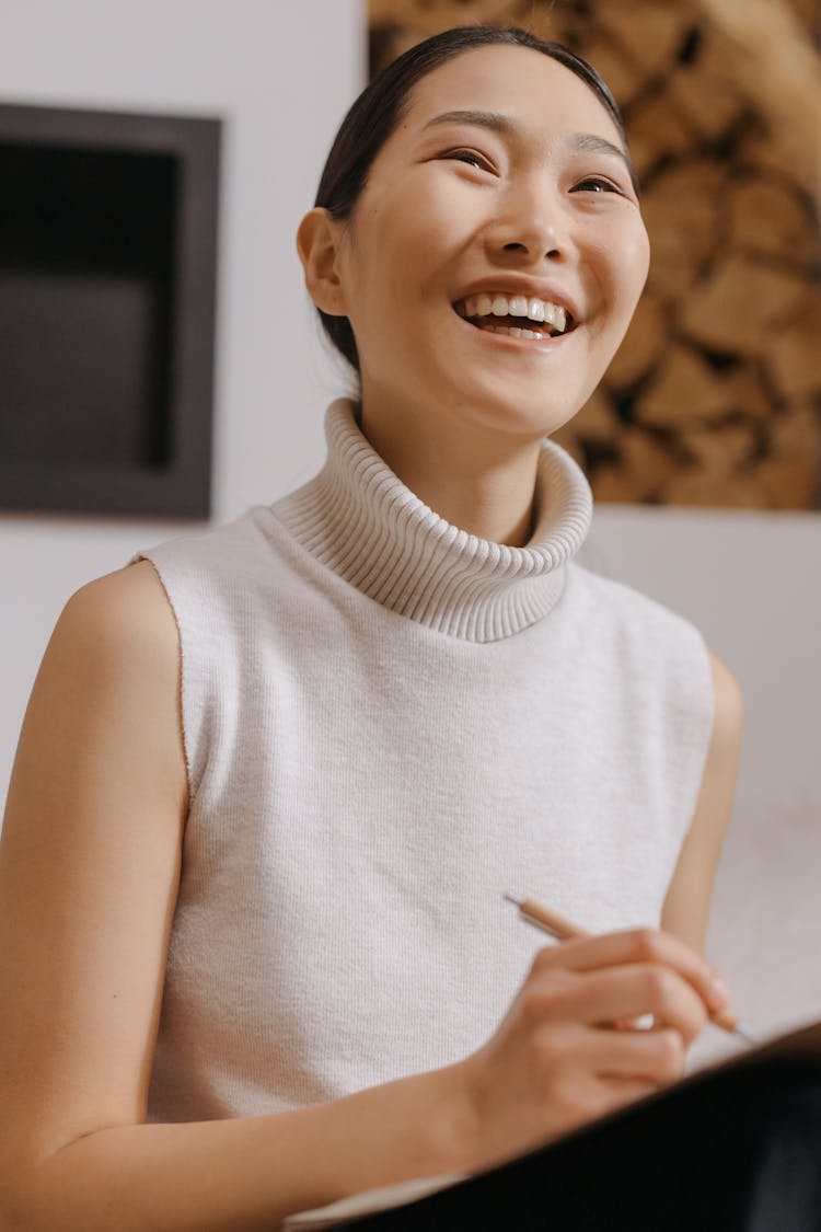 A Smiling Woman Wearing A White Sleeveless Turtleneck Top