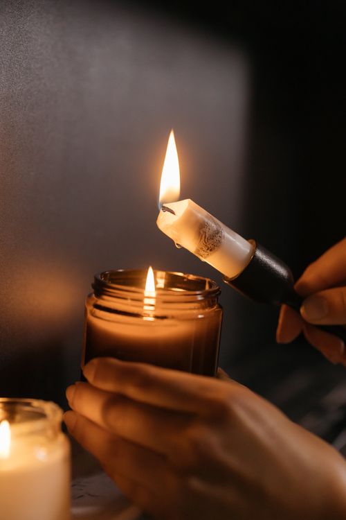 Free Close-up of hands lighting a candle, creating a warm and cozy ambiance indoors. Stock Photo