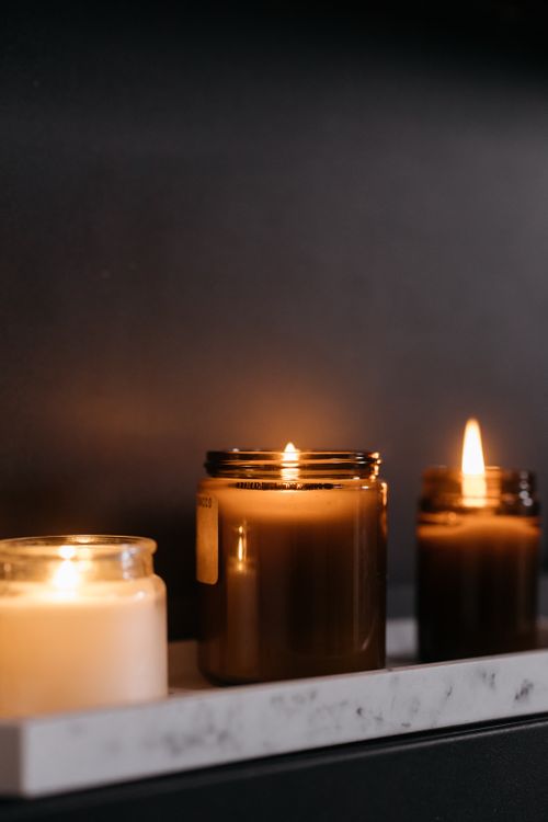 Free A soothing display of burning candles in glass jars on a marble surface. Stock Photo