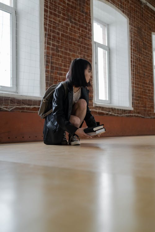 A Woman in Black  Leather Jacket Picking Books