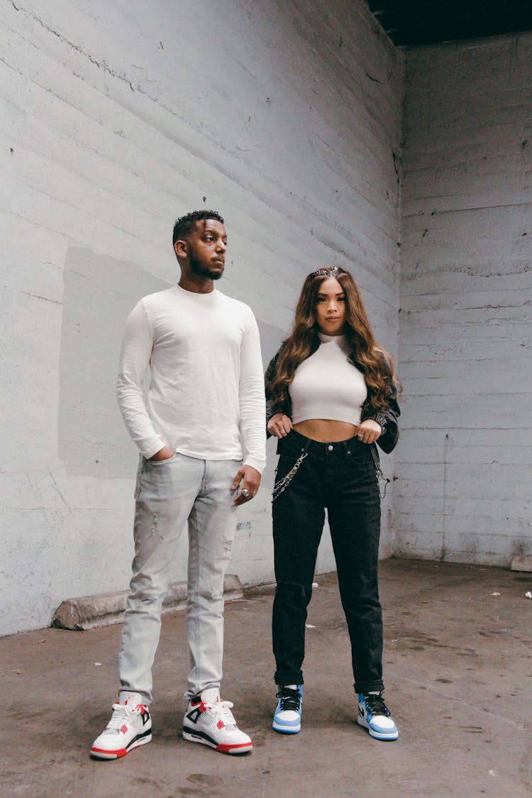 A Man And Woman Wearing Casual Clothes And Sneakers Standing