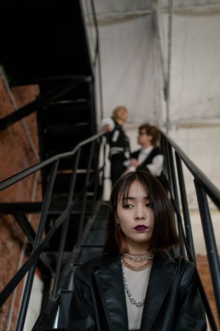 Young woman in black jacket with bold makeup on an industrial staircase.