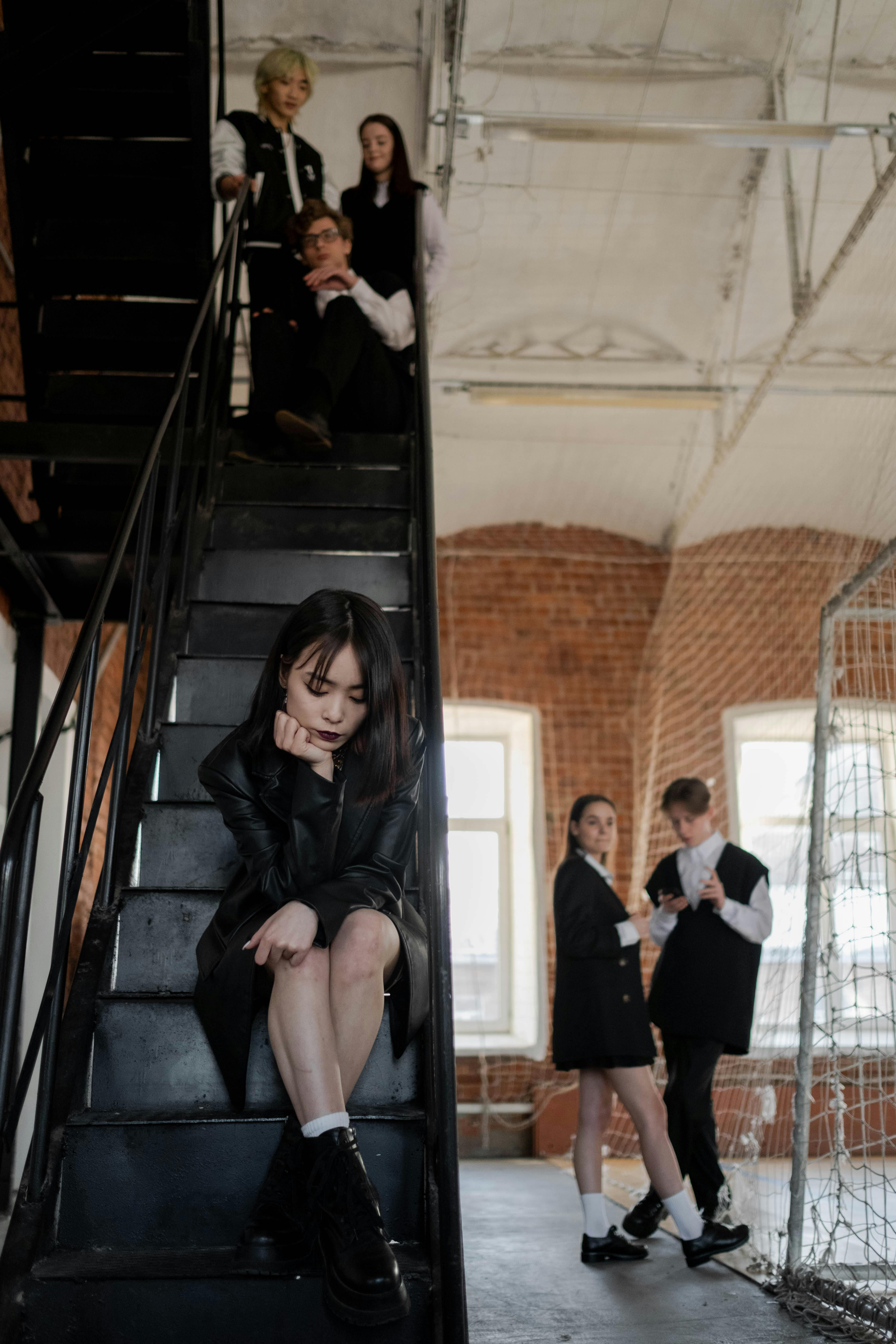 a girl wearing a black long sleeves sitting on a black metal staircase