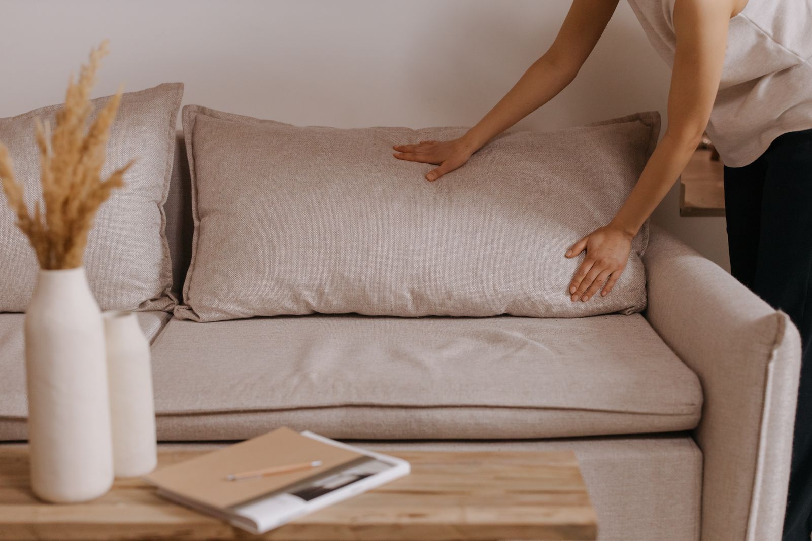 Intérieur rangé et ordonné, mains arrangeant un canapé