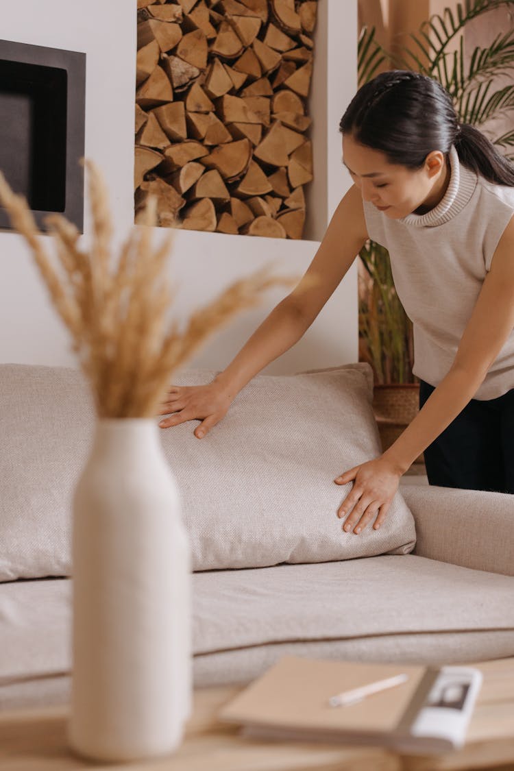 A Woman Arranging The Pillow Of A Sofa