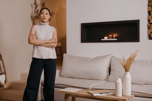 Free A woman stands in a stylish, minimalist living room with a cozy ambiance. Stock Photo