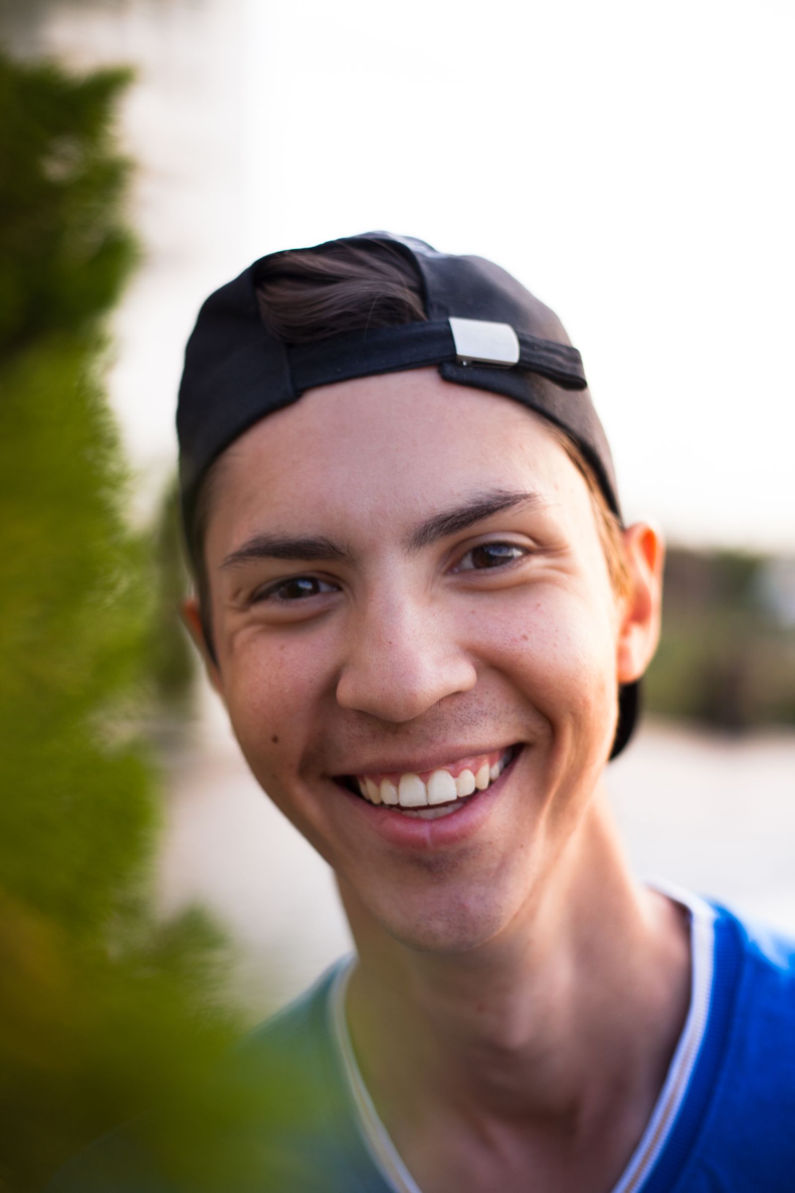 Harshitha smiling outdoors in a cap and red jacket