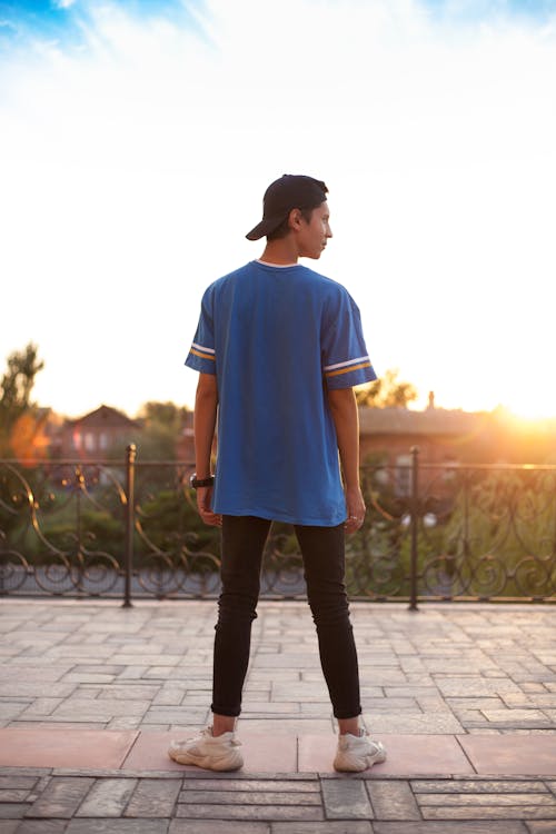 Free A Man in Blue Shirt and Black Pants Standing while Looking Over Shoulder Stock Photo