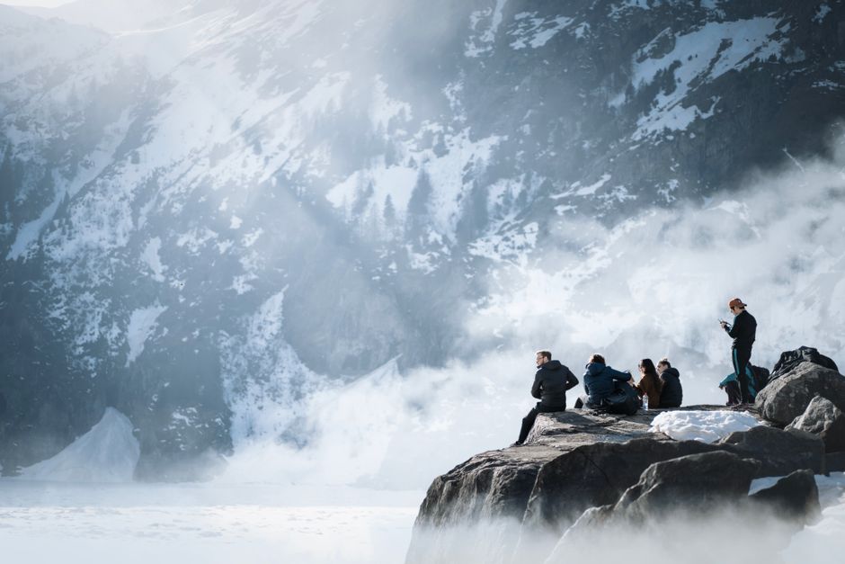 A group of people relaxing on a snowy mountain top amidst stunning winter scenery.