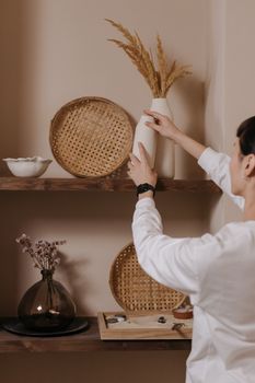Person arranging decorative items on shelves in a cozy indoor setting.