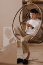 Woman in White Long Sleeve Shirt and Brown Pants Sitting on Brown Wooden Chair