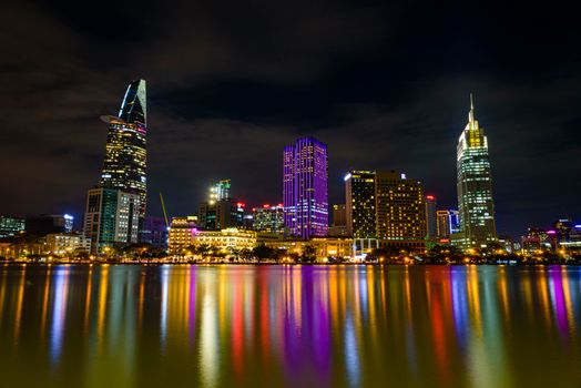 Picturesque view of glowing lights illuminated buildings of modern city reflecting in river at night