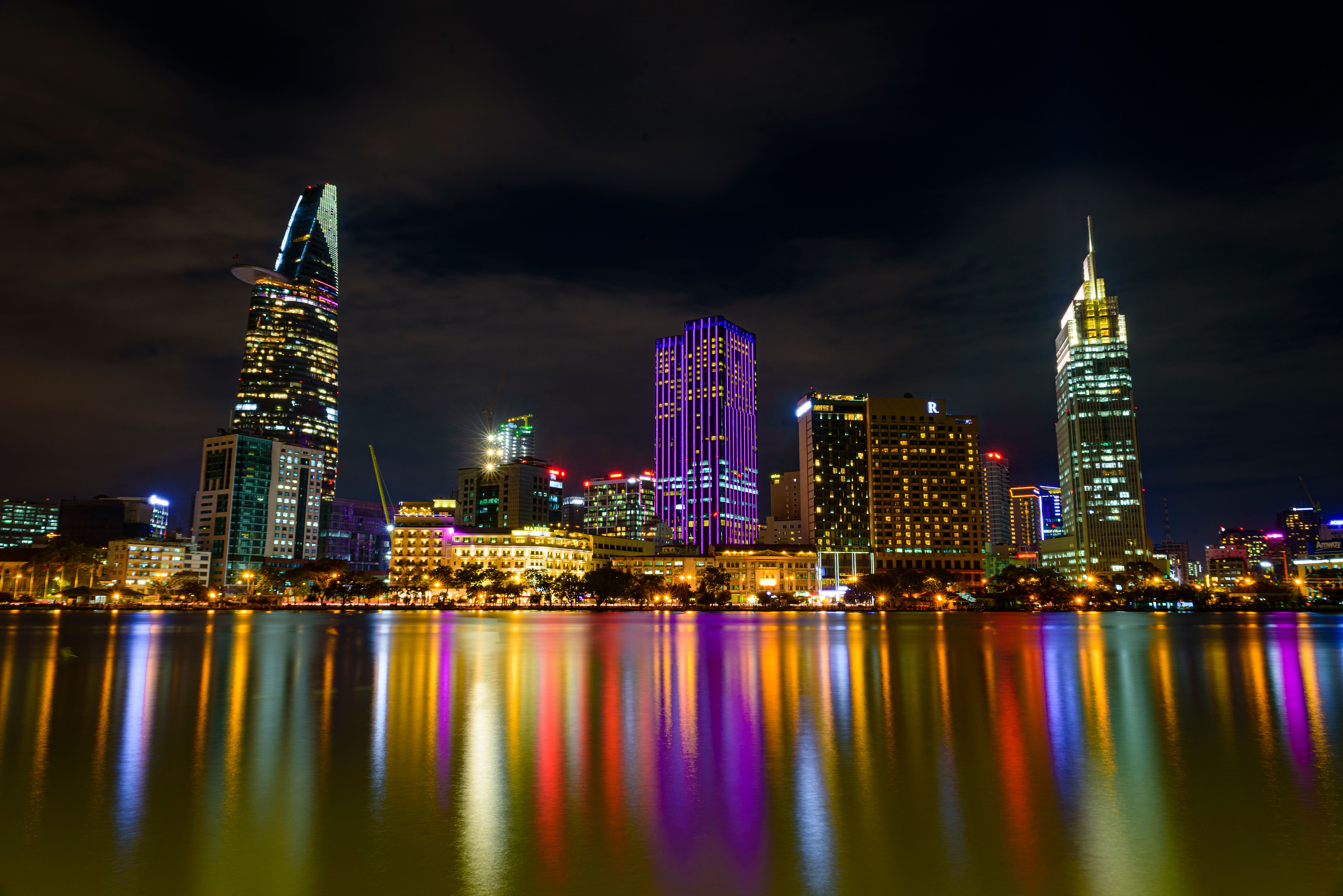 Modern illuminated skyscrapers of city reflecting on river at night ...
