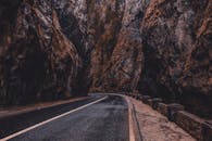 Gray Concrete Road Between Brown Rocky Mountain