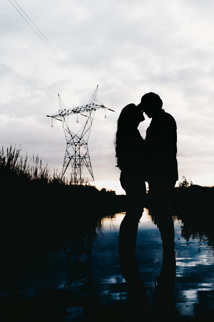 Unrecognizable Couple Silhouette Embracing In River At Night