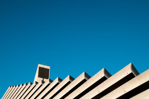 Free Low-angle view of a modern, concrete building exterior with a clear blue sky backdrop. Stock Photo