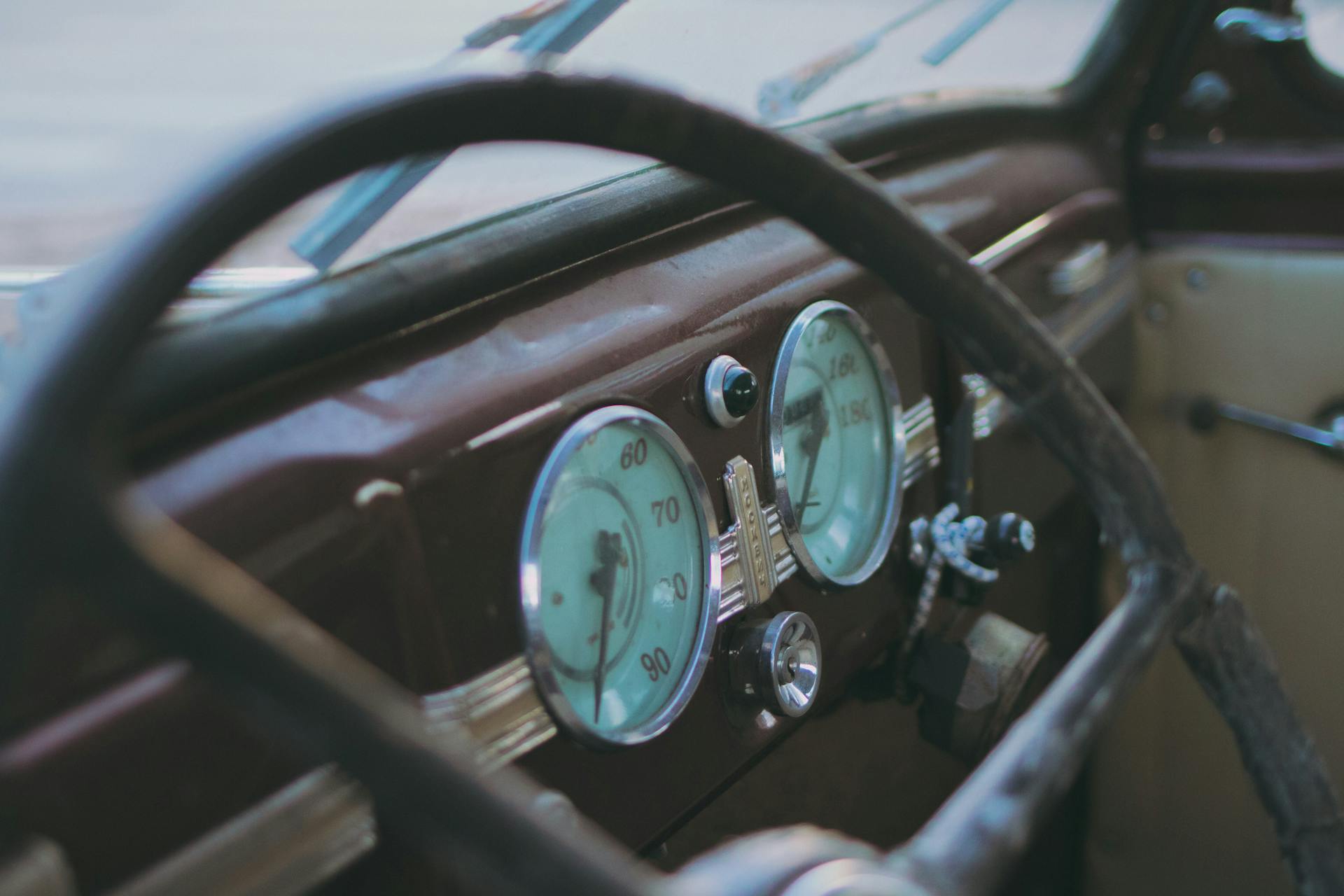 Close-up of a vintage car interior showcasing retro speedometer gauges and a classic steering wheel.