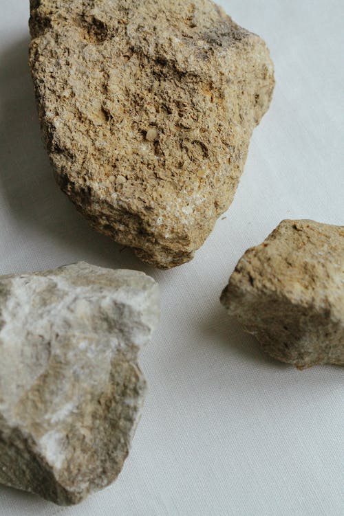 From above of brown and gray carbonate sedimentary rock pieces with rugged surface on light background