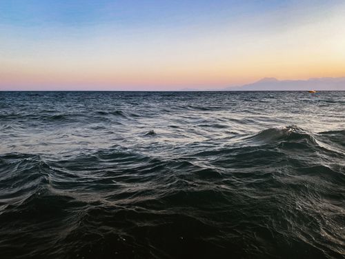 Free Captivating ocean scene with gentle waves under a vibrant sunset sky, perfect for relaxation themes. Stock Photo