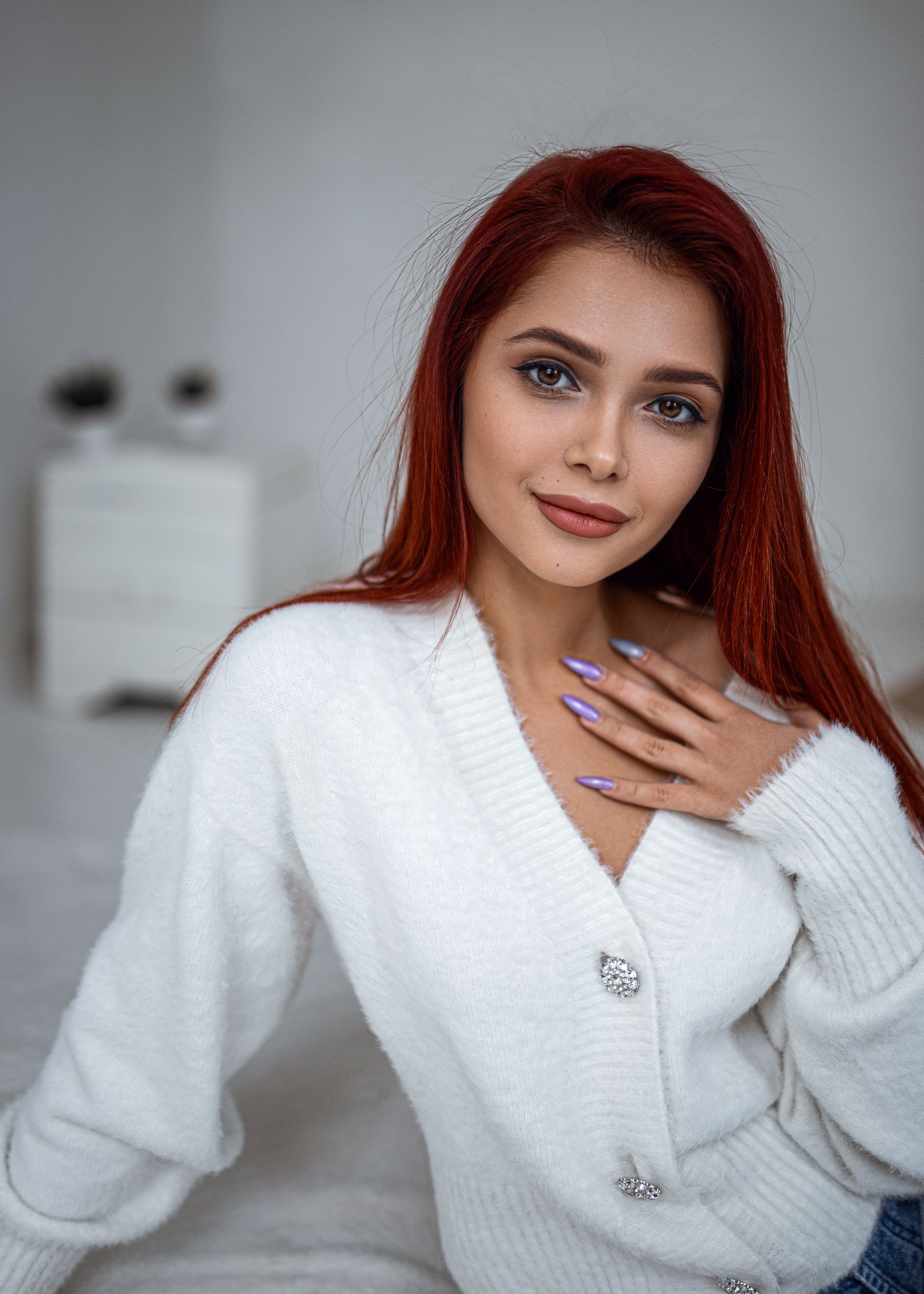 Portrait of a fashionable woman with red hair in a cozy white cardigan.