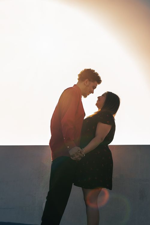 Free A couple holding hands and smiling at each other during a romantic sunset, symbolizing love and togetherness. Stock Photo
