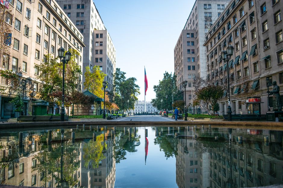 Picturesque urban scene of Santiago with a Chilean flag reflection in the plaza.