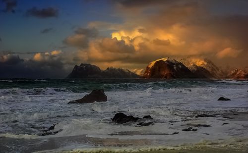 Free Breathtaking sunset over ocean waves and majestic mountains in the background. Stock Photo