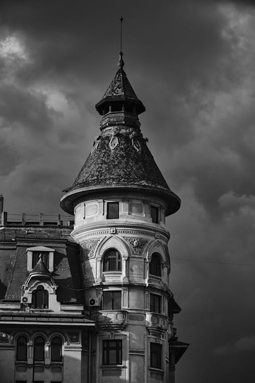 A Grayscale of a Building under a Cloudy Sky