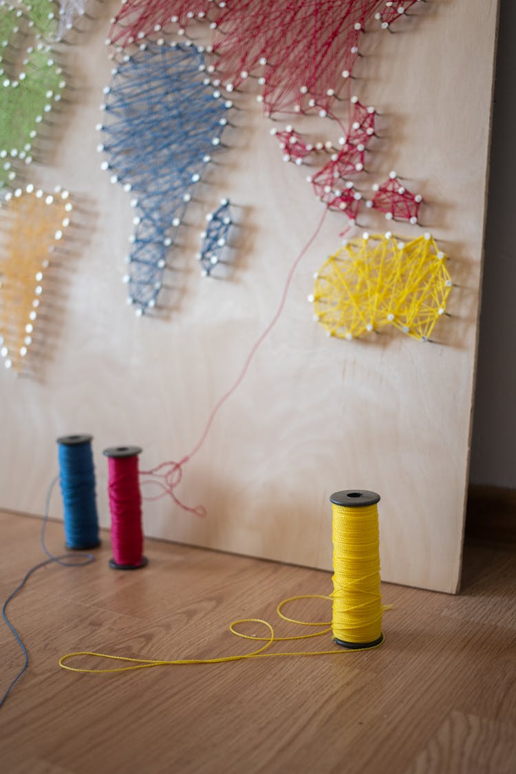 Thread Spools Near String Artwork Of World Map