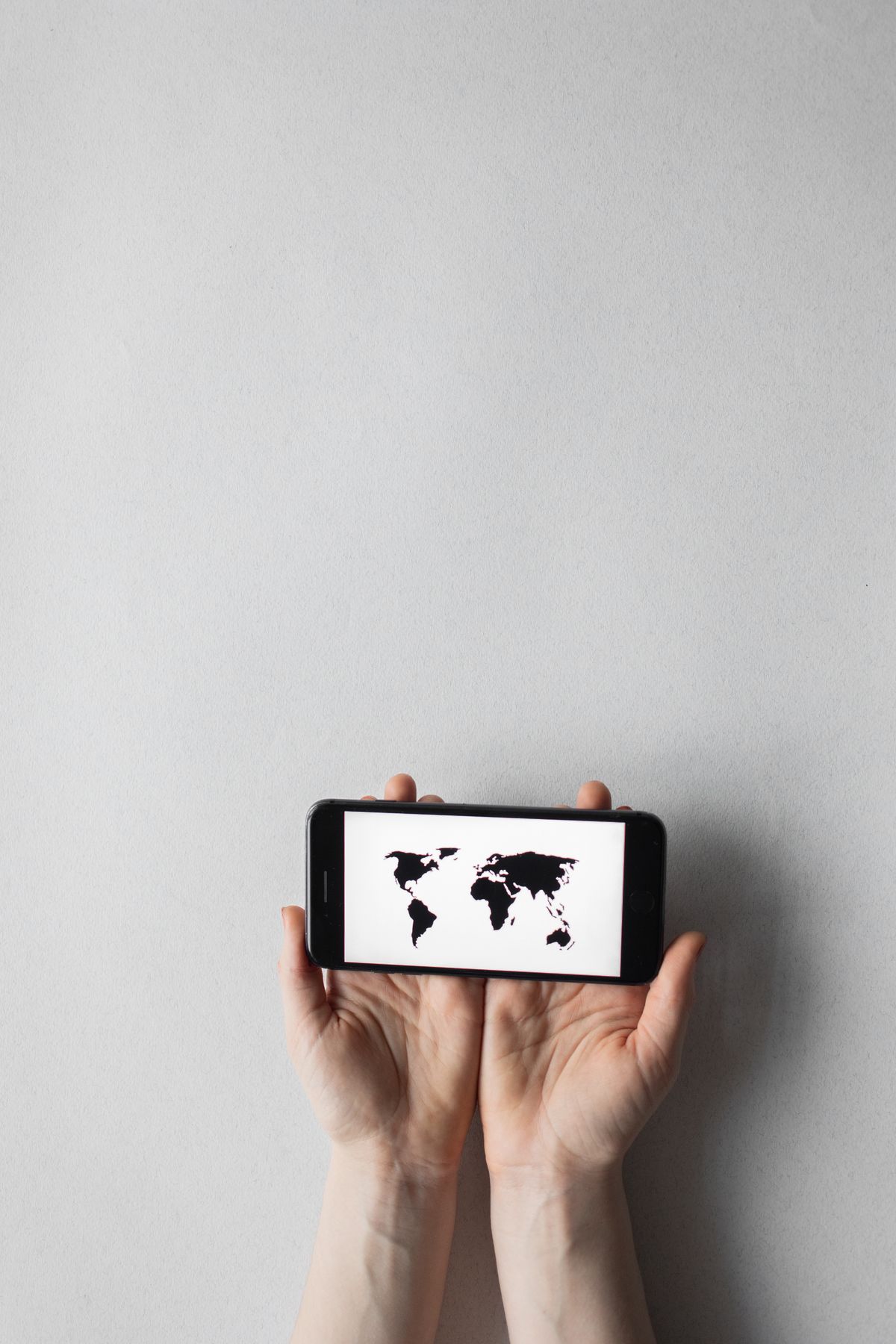 Hands holding a smartphone showing a world map, symbolising the connectivity behind borderless entrepreneurship
