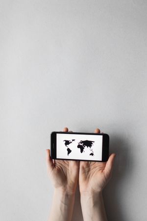Hands holding a phone showing a world map — Monstera Production on Pexels