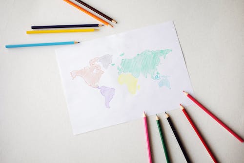 World map drawn on paper sheet near colorful pencils