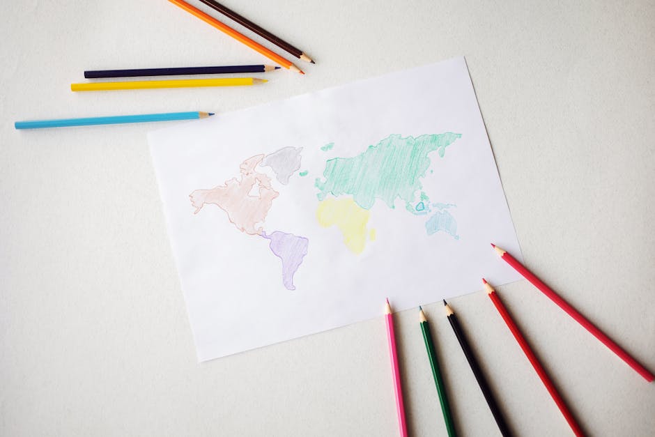 A creative flat lay featuring a hand-drawn world map surrounded by colored pencils on a white background.
