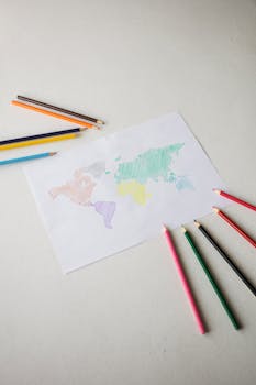 High-angle view of a hand-drawn world map with colored pencils on a white background.