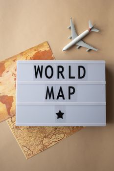 Explore travel concepts with a world map, toy airplane, and lightbox with text.