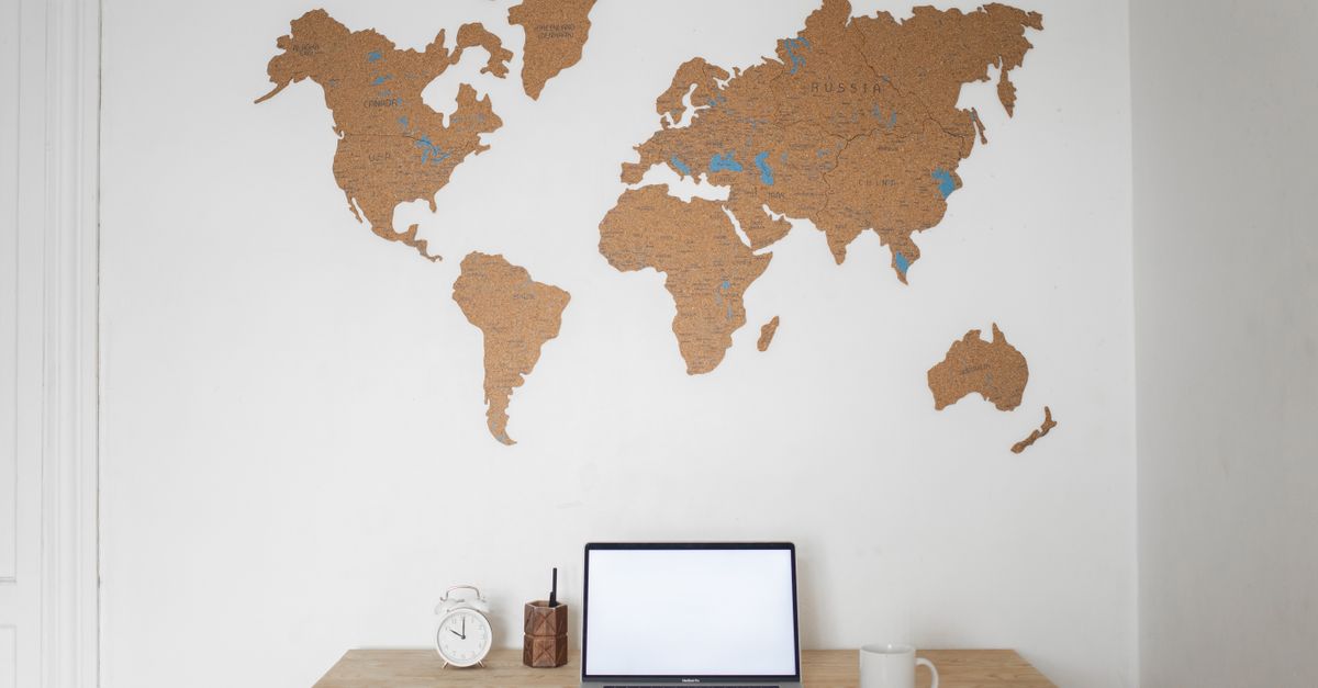digital nomad passport and laptop on a wooden table with a world map background