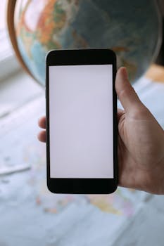 Close-up of a hand holding a smartphone with a blank screen, perfect for mockup or design purposes.