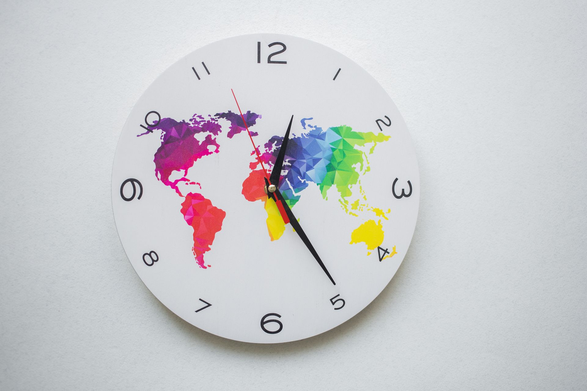 Round wall clock with colorful world map design and black hands, symbolizing global time.