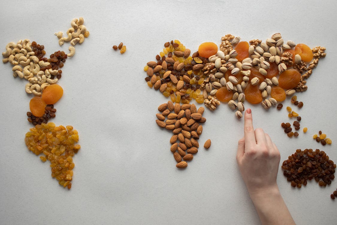 Faceless person making world map with nuts and dried fruits