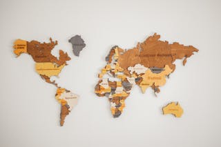 Decorative creative wooden world continents with country names written in Cyrillic attached on white background in light room of studio