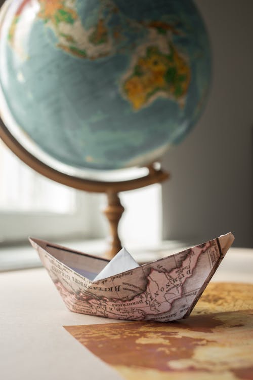 Paper boat with map near globe