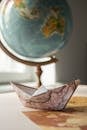 Paper boat with map near globe