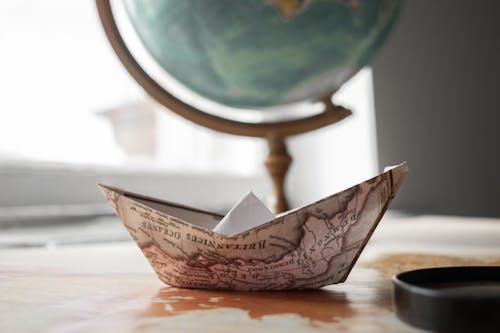 Paper boat near globe in room