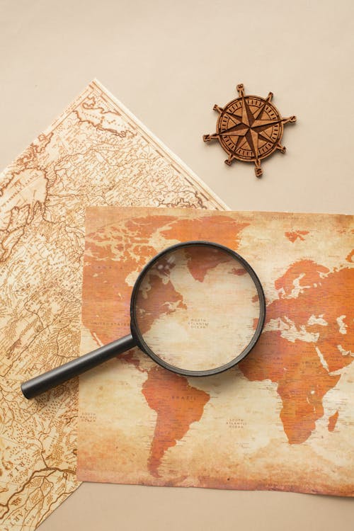 Free Magnifying glass and wind rose on maps Stock Photo